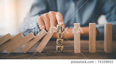close-up hand The hand of a businessman who is stopping or preventing a falling block.Risk protection concept,Eliminating the risk 74109693