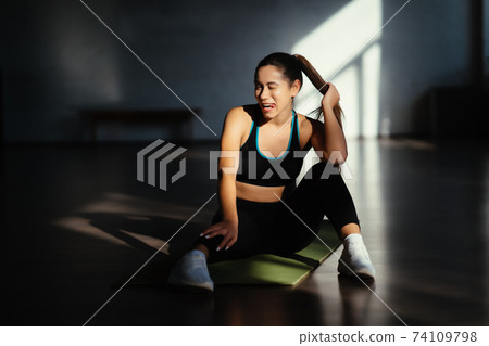 Fit woman resting after home workout, sitting on mat Fit woman resting after home workout, sitting on mat 74109798