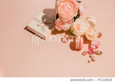 Composition of flowers, gifts and makaruns monochrome peach pastel colors. Trendy spring minimal concept Composition of flowers, gifts and makaruns monochrome peach pastel colors. Trendy spring minimal concept 74110026