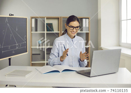 Young Female teacher of geometry communicating with pupil online on laptop 74110135