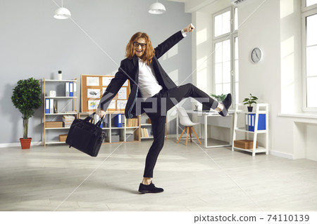 Happy employee with briefcase having fun as it's time to leave office and go home Happy employee with briefcase having fun as it's time to leave office and go home 74110139