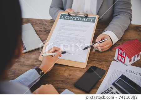 House signers signing signature loan document to home ownership with real estate agents ownership. Mortgage and real estate property investment, home insurance House signers signing signature loan document to home ownership with real estate agents ownership. Mortgage and real estate property investment, home insurance 74110382