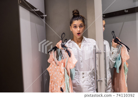 Beautiful girl with lots clothes in room background in a boutique 74110392