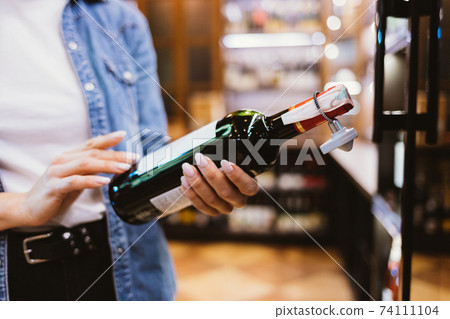 Close-up female hands holding bottle of wine 74111104