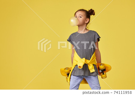 child girl with skateboard blowing a big bubble gum 74111958