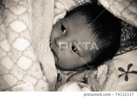 Extreme Closeup portrait of newborn Asian Indian baby boy face just awake from sleep. He just born only 7 days old. Wrapped on white blanket warm clothing. Extreme Closeup portrait of newborn Asian Indian baby boy face just awake from sleep. He just born only 7 days old. Wrapped on white blanket warm clothing. 74112117