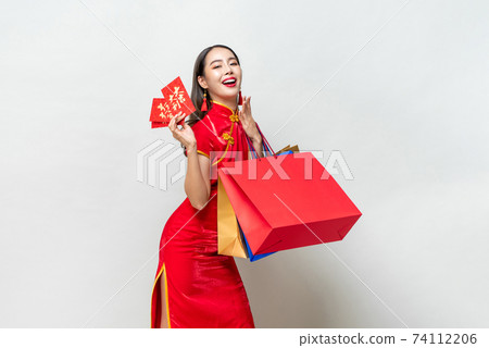 Portrait of Asian woman in traditional dress holding bags and red envelopes in isolated light gray studio background for Chinese new year shopping concept, text means great luck great profit Portrait of Asian woman in traditional dress holding bags and red envelopes in isolated light gray studio background for Chinese new year shopping concept, text means great luck great profit 74112206