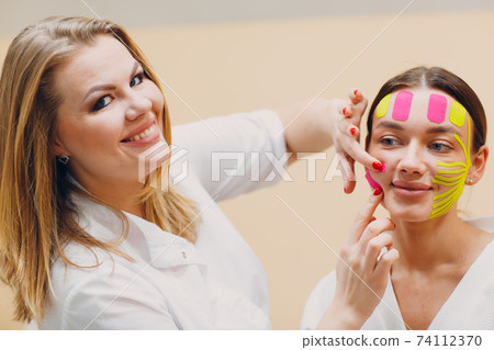 Beautiful woman applying tape lifting treatment on face Beautiful woman applying tape lifting treatment on face 74112370