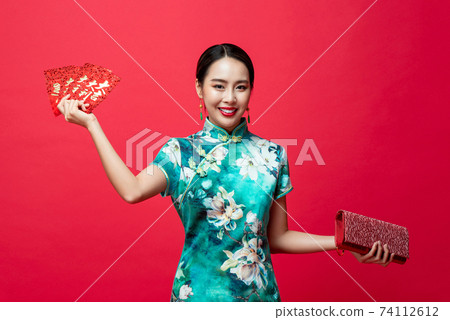 Asian woman wearing qipao dress holding Ang Pao or red envelopes and wallet 74112612