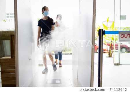 Asian people wear face masks,walk in the automatic disinfection tunnel for disinfecting at gate check point for COVID-19,measures to prevent,make clean and hygienic,new normal life under Coronavirus Asian people wear face masks,walk in the automatic disinfection tunnel for disinfecting at gate check point for COVID-19,measures to prevent,make clean and hygienic,new normal life under Coronavirus 74112642