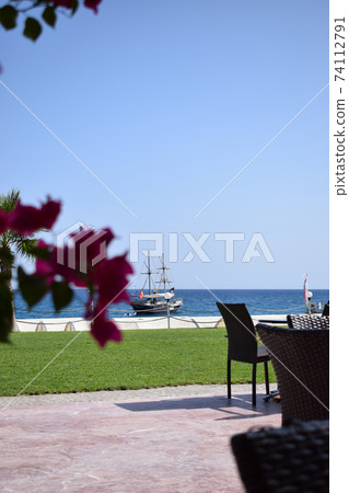 A cozy cafe with beautiful views of the blue sea and the sailing ship in a pirate style. 74112791