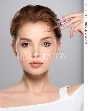 Woman getting cosmetic injection of botox in forehead, closeup. Woman in beauty salon, plastic surgery clinic. Cosmetology procedures concept. Beauty treatment therapy. Woman getting cosmetic injection of botox in forehead, closeup. Woman in beauty salon, plastic surgery clinic. Cosmetology procedures concept. Beauty treatment therapy. 74114123