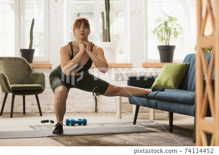 Young woman exercising fitness, aerobic, yoga at home, sporty lifestyle. Getting active during lockdown, quarantine. Home gym. Young woman exercising fitness, aerobic, yoga at home, sporty lifestyle. Getting active during lockdown, quarantine. Home gym. 74114452