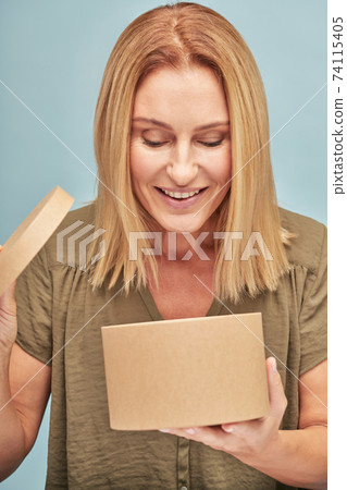 Smiling beautiful adult lady opening gift box 74115405