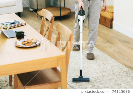 Woman vacuuming in her living room 74115686