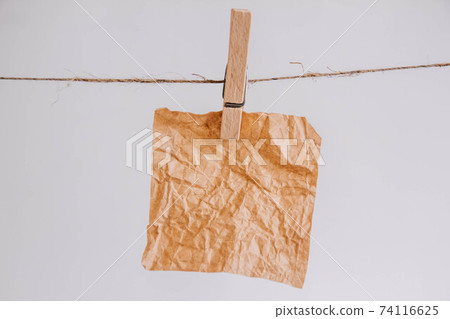 Brown stickers on clothesline with wooden clothespin isolated on white background. Place for your text Brown stickers on clothesline with wooden clothespin isolated on white background. Place for your text 74116625