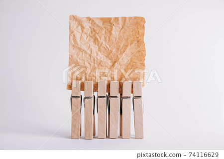 Woodenl clothespins, paper clip and brown sticker on white background. Isolated on white. Place for your text Woodenl clothespins, paper clip and brown sticker on white background. Isolated on white. Place for your text 74116629