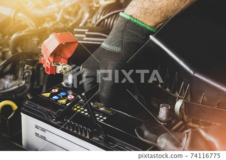 The Mechanic hand is pulling up an car old battery for replacement 74116775