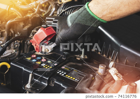 The Mechanic hand is fasten the bolt with the open-end wrench to replacement of the car old battery 74116776