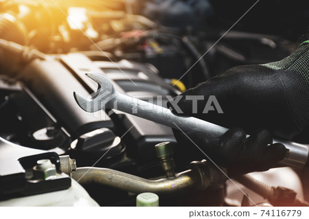 The Mechanic hand holding open-end wrench with a sunlight and engine blurred on background The Mechanic hand holding open-end wrench with a sunlight and engine blurred on background 74116779