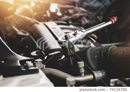The Mechanic hand is fasten the bolt with the socket wrench to repairing of the car engine 74116780