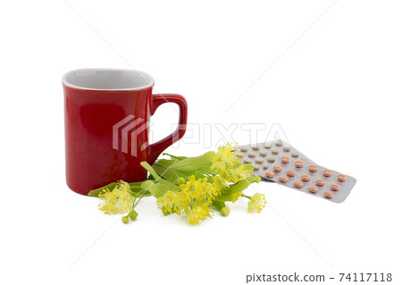 Red cup near yellow linden flowers and pills 74117118