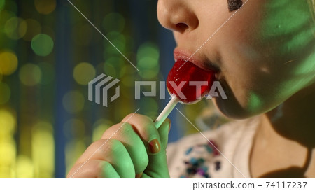 Futuristic hipster teen girl licking lollipop candy in slow motion at disco party cyberpunk club 74117237
