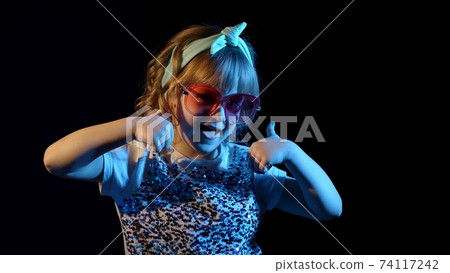 Trendy stylish girl dancing alone, showing thumbs up in futuristic night club with neon lights Trendy stylish girl dancing alone, showing thumbs up in futuristic night club with neon lights 74117242