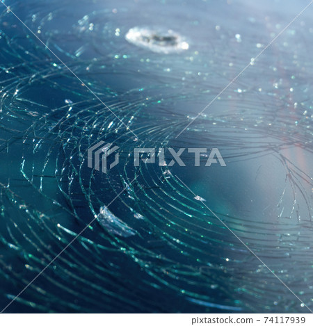 background of blue car broken windshield covered with circles of cracks. Hole on windscreen. 74117939