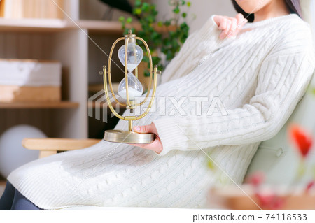 Pregnant woman with hourglass Thinking scheduled date remaining time countdown image 74118533