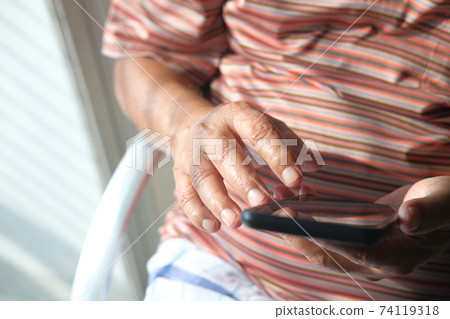 Close up of senior man hand using smart phone at home  74119318