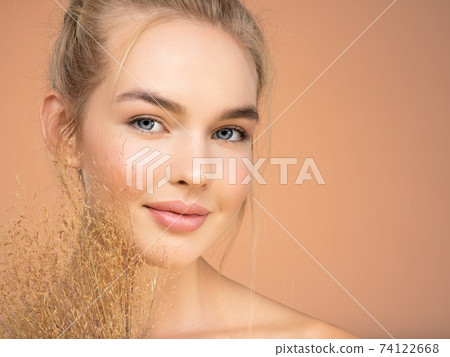 Portrait of young beautiful woman with a healthy  skin of face.  Attractive girl with a bunch spring field flowers 74122668