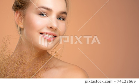 Portrait of young smiling woman with a healthy  skin of a face. Happy girl with a spring field flowers 74122669
