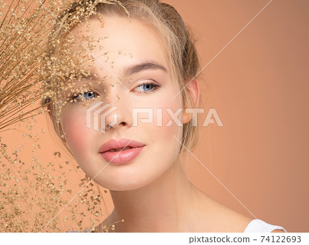Portrait of young beautiful woman with a healthy  skin of face.  Attractive girl with a bunch spring field flowers 74122693