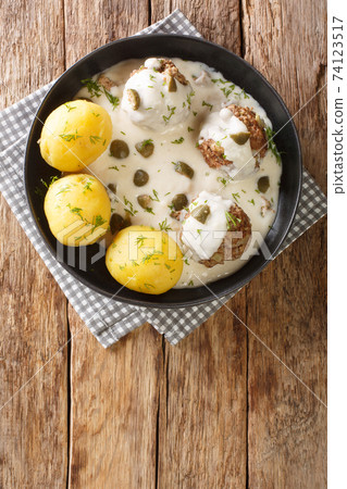 Konigsberger Klopse, also known as Sobklopse are a German specialty of meatballs in a white sauce with capers close-up in a plate. vertical top view 74123517