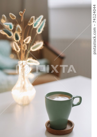 Cup of coffee and a transparent vase with dried flowers at white background 74124044