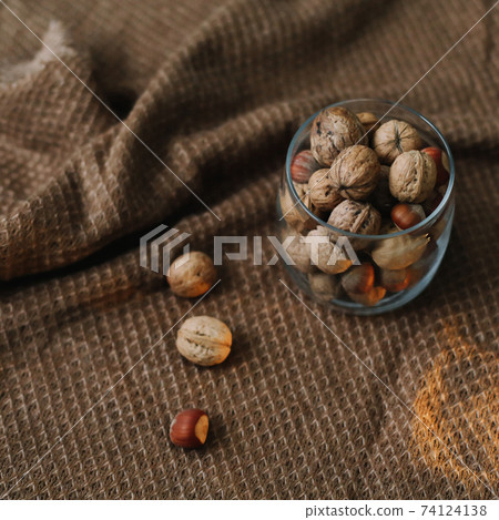 Mix of nuts in a jar on dark background. Walnuts and pine nuts. Top view. Copy space. Superfood, vegan, vegetarian food concept. Macro of walnut texture. selective focus. Healthy snack. 74124138