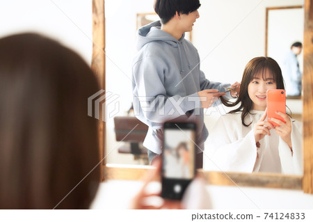 在美容院拿著智能手機的女顧客 在美容院拿著智能手機的女顧客 74124833