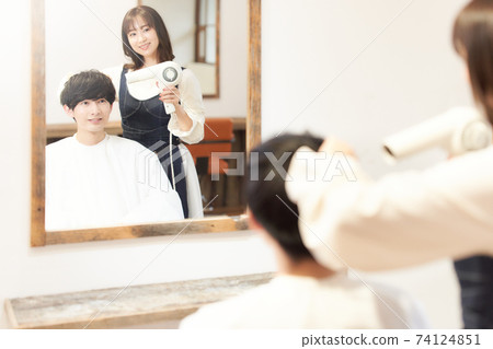 Male customer having a stylist dry his hair Male customer having a stylist dry his hair 74124851