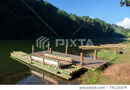 The bamboo raft is floating near the wooden pier. 74125074
