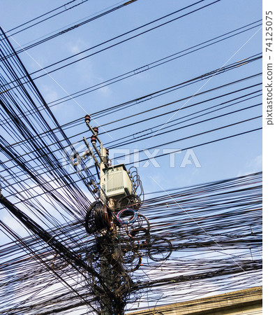 The communication cables are entangled on the electric pole. 74125075