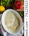 Raw halibut fish fillet, tomato, lemon, green basil and spices. White casserole on wooden rustic table, top view 74125623