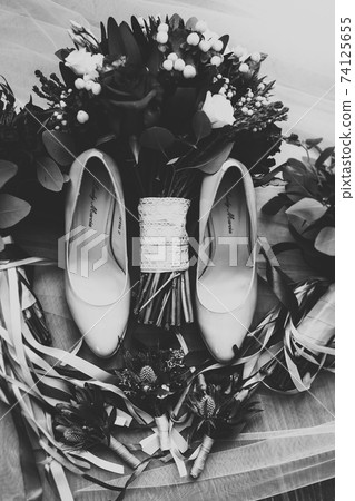 Pair of elegant and stylish bridal shoes and a bouquet of roses and other flowers Pair of elegant and stylish bridal shoes and a bouquet of roses and other flowers 74125655