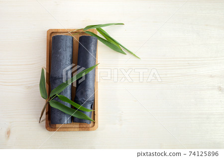Natural Bamboo ativated charcoal on white wooden background Natural Bamboo ativated charcoal on white wooden background 74125896