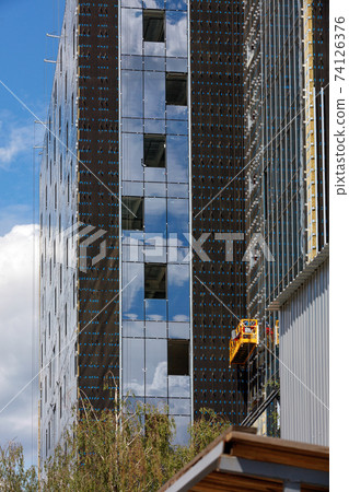Reconstruction, facade insulation and installation of large windows in a modern residential building using a winch and a mobile platform. 74126376