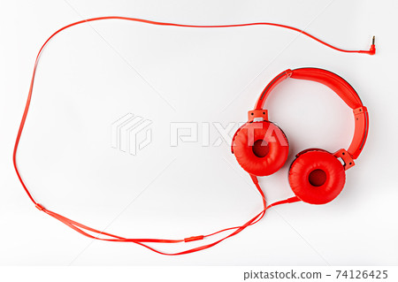 Red round headphones with a cord forming a frame flat lay on a white background with a copy space Red round headphones with a cord forming a frame flat lay on a white background with a copy space 74126425