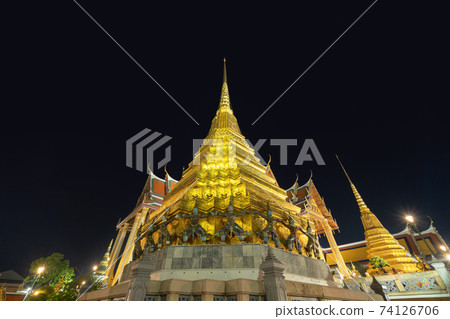 Golden pagoda at Temple of the Emerald Buddha in Bangkok, Thailand. Wat Phra Kaew and Grand palace in old town, urban city. Buddhist temple, Thai architecture. A tourist attraction at night. 74126706