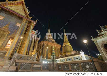 Golden pagoda at Temple of the Emerald Buddha in Bangkok, Thailand. Wat Phra Kaew and Grand palace in old town, urban city. Buddhist temple, Thai architecture. A tourist attraction at night. 74126708