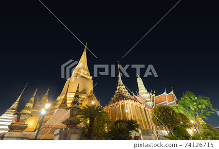Golden pagoda at Temple of the Emerald Buddha in Bangkok, Thailand. Wat Phra Kaew and Grand palace in old town, urban city. Buddhist temple, Thai architecture. A tourist attraction at night. 74126715