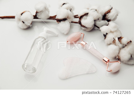 Gua Sha massager and jade roller on white background with cotton. Face and body care concept Gua Sha massager and jade roller on white background with cotton. Face and body care concept 74127265